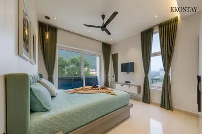 a bedroom with a bed and a large window at EKOSTAY - Amber Villa in Kodaikānāl