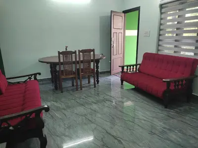 a living room with a red couch and a table at Green wayanad homestay in Kenichira
