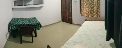 a room with a table and a chair and a table and a bed at Aswathy Bhavan in Vadakkāncheri