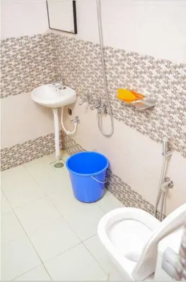 a bathroom with a sink and a toilet and a bucket at Cardamom Garden Homestay Meppadi Wayanad in Meppādi