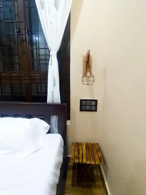 a bedroom with a bed and a table next to a window at Tranquil Traditions Homestay - Inspired by Nature & Heritage in Mysore