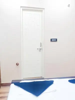 a bed with a blue pillow in front of a door at Tranquil Traditions Homestay - Inspired by Nature & Heritage in Mysore