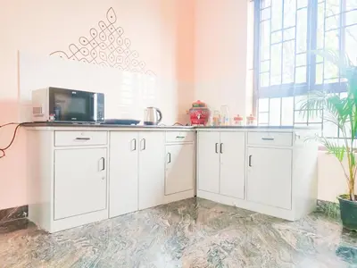 a kitchen with white cabinets and a microwave at Tranquil Traditions Homestay - Inspired by Nature & Heritage in Mysore