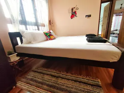 a bedroom with a large bed with white sheets at Tranquil Traditions Homestay - Inspired by Nature & Heritage in Mysore
