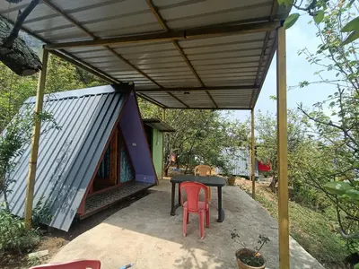 a tent with a table and chairs on a patio at Croods cabin in Kodaikānāl