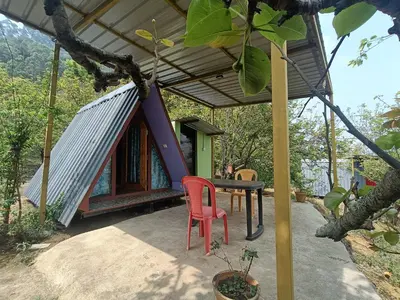 a small house with a table and a red chair at Croods cabin in Kodaikānāl