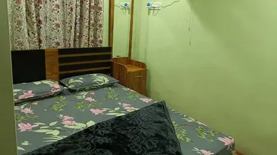 a bedroom with a bed with a floral bedspread at Ammavvana Kutira Home stay in Madikeri