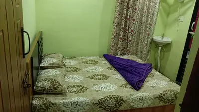 a small bed with purple pillows in a room at Ammavvana Kutira Home stay in Madikeri