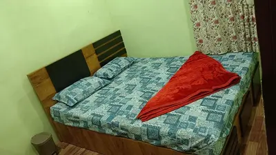 a bed with a red pillow on top of it at Ammavvana Kutira Home stay in Madikeri
