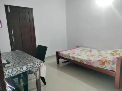 a room with a bed and a table and a door at Aswathy Bhavan in Vadakkāncheri