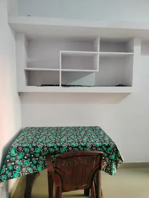 a room with a table and a chair and shelves at Aswathy Bhavan in Palakkad