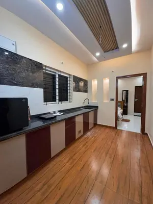 a large kitchen with a counter and a wooden floor at G3 nest in Mysore