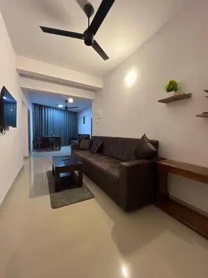 a living room with a couch and a ceiling fan at Hotel Le Marina Residency in Kozhikode