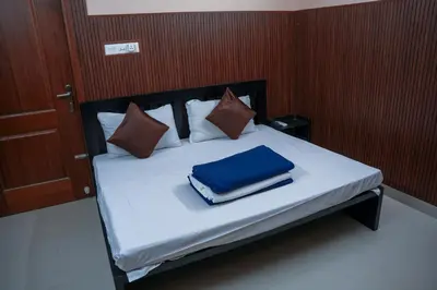 a bed with a blue blanket and pillows on it at Sancta Maria Lounge -cochin Airport in Nedumbassery