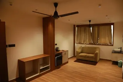 a living room with a ceiling fan and a chair at Marina Tower & Regency Changaramkulam in Edappāl