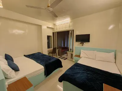 a hotel room with two beds and a flat screen tv at Cocoa Tree Munnar in Munnar