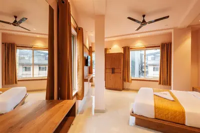 a bedroom with two beds and two windows at Hotel Beverly Palace Kozhikode - Hotel and Restaurant in Kozhikode