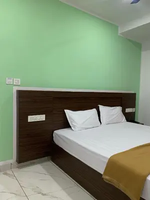 a bed with a wooden headboard in a room at Adi Deva Inn in Guruvāyūr