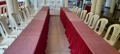 a row of red tables and chairs in a room at Adi Deva Inn in Guruvāyūr