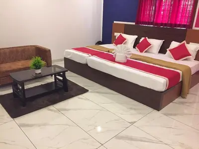 a bedroom with two beds with red pillows and a table at Adi Deva Inn in Guruvāyūr