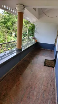 an empty room with a large window and a wooden floor at VELLAKUZHY Homestay Wayanad in Wayanad