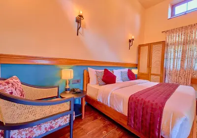 a bedroom with a bed and a table and chairs at Mowbray House Resort Ooty by VOYE HOMES in Ooty