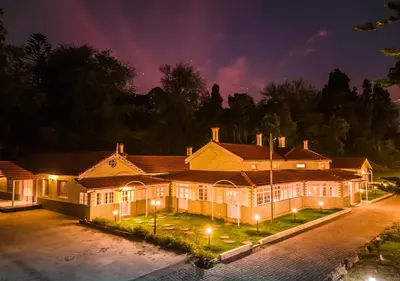 a large house is lit up at night at Mowbray House Resort Ooty by VOYE HOMES in Ooty