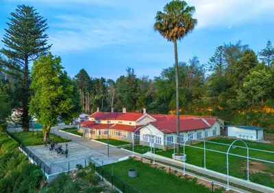 a house with a red roof and a palm tree at Mowbray House Resort Ooty by VOYE HOMES in Ooty