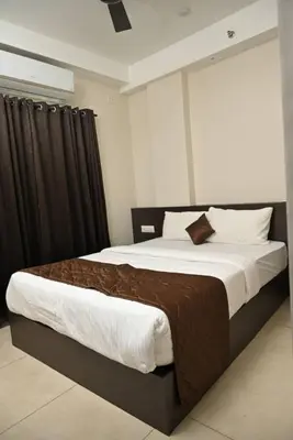 a bedroom with a large bed with brown and white sheets at Guruvayoor Suits Pankaj Suits in Trichūr