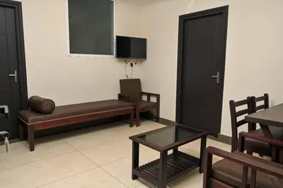 a living room with a bench and a table and chairs at Guruvayoor Suits Pankaj Suits in Trichūr