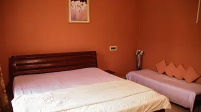 two beds in a bedroom with orange walls at Coorgglade in Kakkabe
