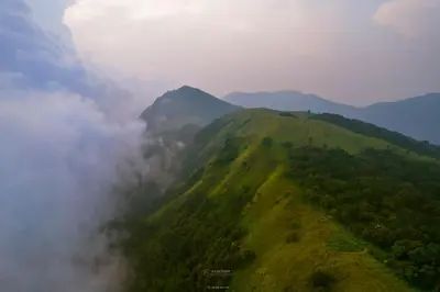 an aerial view of a mountain with clouds and trees at Coorgglade in Kakkabe