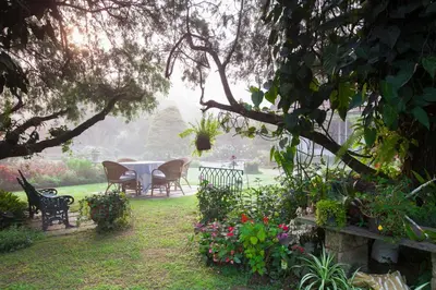 a table and chairs in a garden with flowers at The School Estate in 100 Acres in Siddapur