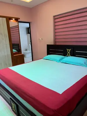 a bedroom with a large bed with blue and red sheets at Sunset View Inn in Irinjālakuda