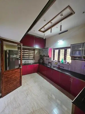 a large kitchen with red cabinets and red counters at Sunset View Inn in Irinjālakuda