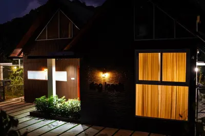 a house with lights on the side of it at night at Fog Land Pool Villa by BMT in Vythiri
