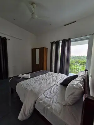 a bedroom with a bed and a large window at Parthees Homestay in Meppādi
