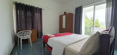 a bedroom with a bed and a window and a chair at Parthees Homestay in Meppādi