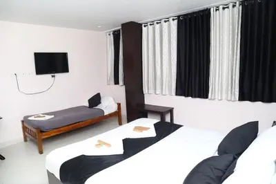 a hotel room with two beds and a tv at Erica Hotel International in Perintalmanna
