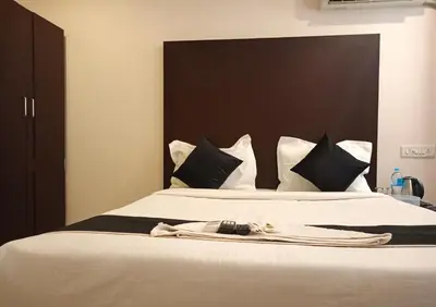 a bedroom with a large white bed with black pillows at Erica Hotel International in Perintalmanna