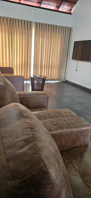 a waiting room with brown leather chairs and a screen at Royal Heaven in Ambalavayal