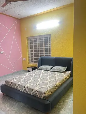 a bed in a room with yellow and pink at Chamundi Temple-Hill View in Mysore