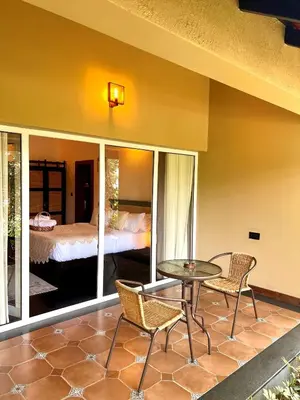 a patio with a table and chairs and a bed at Tangerine Tales Boutique Resort By LexStays in Wayanad