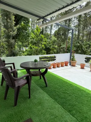 a patio with a table and chairs on grass at Anya Retreats Nature Homestay in Kushālnagar