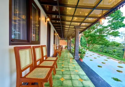 a row of chairs sitting on a porch with at Whispering Hills Pine Malhar Pool & Tent Attappadi by VOYE HOMES in Attappādi