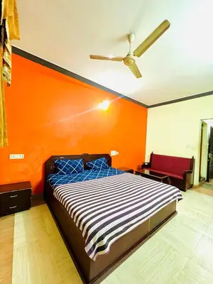 a bed in a room with an orange wall at Hotel Alsaj in Alwaye