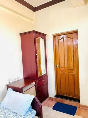 a bedroom with a wooden cabinet and a bed and a mirror at Hotel Alsaj in Alwaye