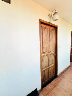 a wooden door in a room with a white wall at Hotel Alsaj in Alwaye