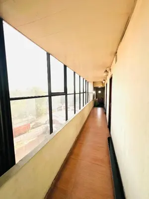 an empty corridor in a building with large windows at Hotel Alsaj in Alwaye