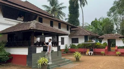 a man standing in front of a house at SaffronStays Amaya - 5BR 300-year-old Kerala-style heritage villa with spa near Kannur Airport in Irikkūr
